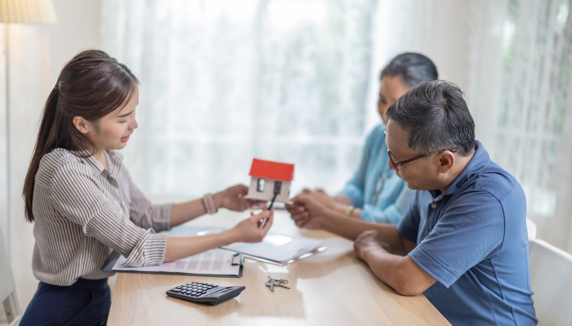 Elderly couples satisfying retirement home purchase with contract and key handover from a saleswoman